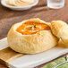 A bowl of soup with a Rich's mini French bread boule on top of it.