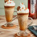 A glass cup of coffee with SHOTT Butterscotch Flavoring Syrup on a table.