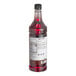A close-up of a Monin Wild Raspberry Flavoring Syrup bottle with a label.