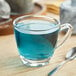 A glass of blue liquid on a table.