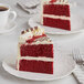 A slice of red velvet cake on a plate with Chefmaster Red Dry Powder Food Color on a table.