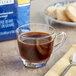 A cup of Lavazza coffee with a bag of Lavazza coffee beans on a table.