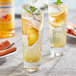 A glass of iced peach tea with mint leaves and fruit slices using Monin Sugar Free Peach Flavoring.