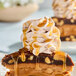 A slice of caramel and nut dessert topped with whipped cream and caramel sauce.
