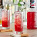 A glass of Finest Call Cranberry Juice with ice and a rosemary sprig on the rim.