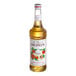 A white labeled bottle of Monin peach syrup.