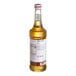 A bottle of Monin peach syrup with a white label.