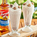 A glass of chocolate milk with a straw and a cookie on the rim using Torani Chocolate Chip Cookie Dough flavoring syrup.