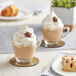 Two glass cups of David Rio Tiger Spice Chai Tea Latte with whipped cream and star anise on top on a table.