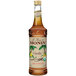 A bottle of Monin Organic Vanilla Flavoring Syrup with a brown liquid and a label.