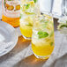 Two glasses of yellow Monin mango drinks with mint leaves and ice.