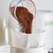 A measuring cup full of Toddy Blend coarse ground coffee being poured.