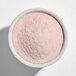 A white bowl filled with fine pink powder mix.