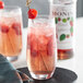 A glass of pink raspberry drink with a straw and raspberry on top.