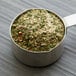 A metal measuring cup filled with Regal Herbs & Garlic Blend.