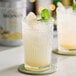 A glass of Monin ginger liquid with mint leaves on a coaster.