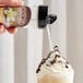 A hand pouring UPOURIA French Vanilla coffee topping onto a cup of whipped cream.