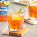 A glass of Torani sugar-free orange drink with a slice of lemon and rosemary.