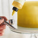 A person using a Chefmaster metallic gold airbrush to spray color onto a cake.