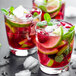 A glass of Smartfruit Wild Watermelon beverage with fruit and a lime wedge on the rim.