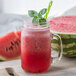 A glass jar filled with red Smartfruit Wild Watermelon beverage with a straw.