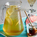 A pitcher of lemonade with DaVinci Gourmet Classic Honey Sweetener Syrup on a table.