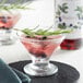 A glass of Monin Blueberry flavoring with a drink and a sprig of rosemary.