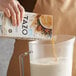 A person pouring milk into a pitcher.