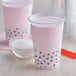 A pink bubble tea drink in a plastic cup with black dots in it.