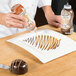 A person pouring caramel sauce on a chocolate dessert with a crisscrossed design using a Smucker's Caramel Platescapers bottle.