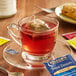 A glass cup of Bigelow herbal tea with a tea bag on a saucer.