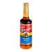 A Torani Pumpkin Spice flavoring syrup 750 mL glass bottle on a table with a label.