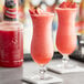 Two glasses with strawberry drinks on a table.