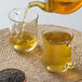 A person pouring Numi Organic loose leaf tea into a glass mug.