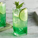 A glass of green drink with DaVinci Gourmet Sugar Free Lime Flavoring and lime slices.