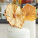 A close-up of a Blue Henry dried pineapple slice being dipped into a glass of liquid.