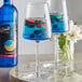 Two wine glasses of blue liquid with fruit in it.