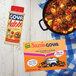 A package of 18 Goya Sazon seasoning packets on a white background next to a pan of food with meat and vegetables.