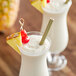 A glass of Island Oasis Pina Colada with a straw next to another glass of the same drink.