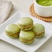 A plate of green and brown macarons with a bowl of green powder.