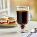 A glass of Cafe Bustelo espresso on a table with desserts.