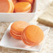 A white plate of orange Chefmaster macaroons.