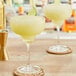 Two glasses of DaVinci Gourmet Margarita cocktail mix with yellow liquid and a lime wedge.
