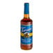 A Torani Sugar-Free Brown Sugar Cinnamon flavoring syrup bottle with a blue label filled with brown liquid.