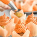 A close-up of a cupcake with orange Chefmaster Liqua-Gel frosting.