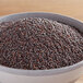 A bowl of brown mustard seeds on a wooden table.