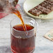 A person pouring Numi Organic Aged Pu-Erh Tea into a glass.