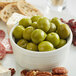 A white bowl filled with green Castelvetrano olives.