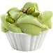 A cup of green pistachio ice cream with nuts.
