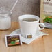 A white cup of Bromley Exotic Cool Mountain Mint tea with a tea bag on a saucer.